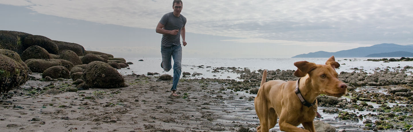 man running on beach with dog